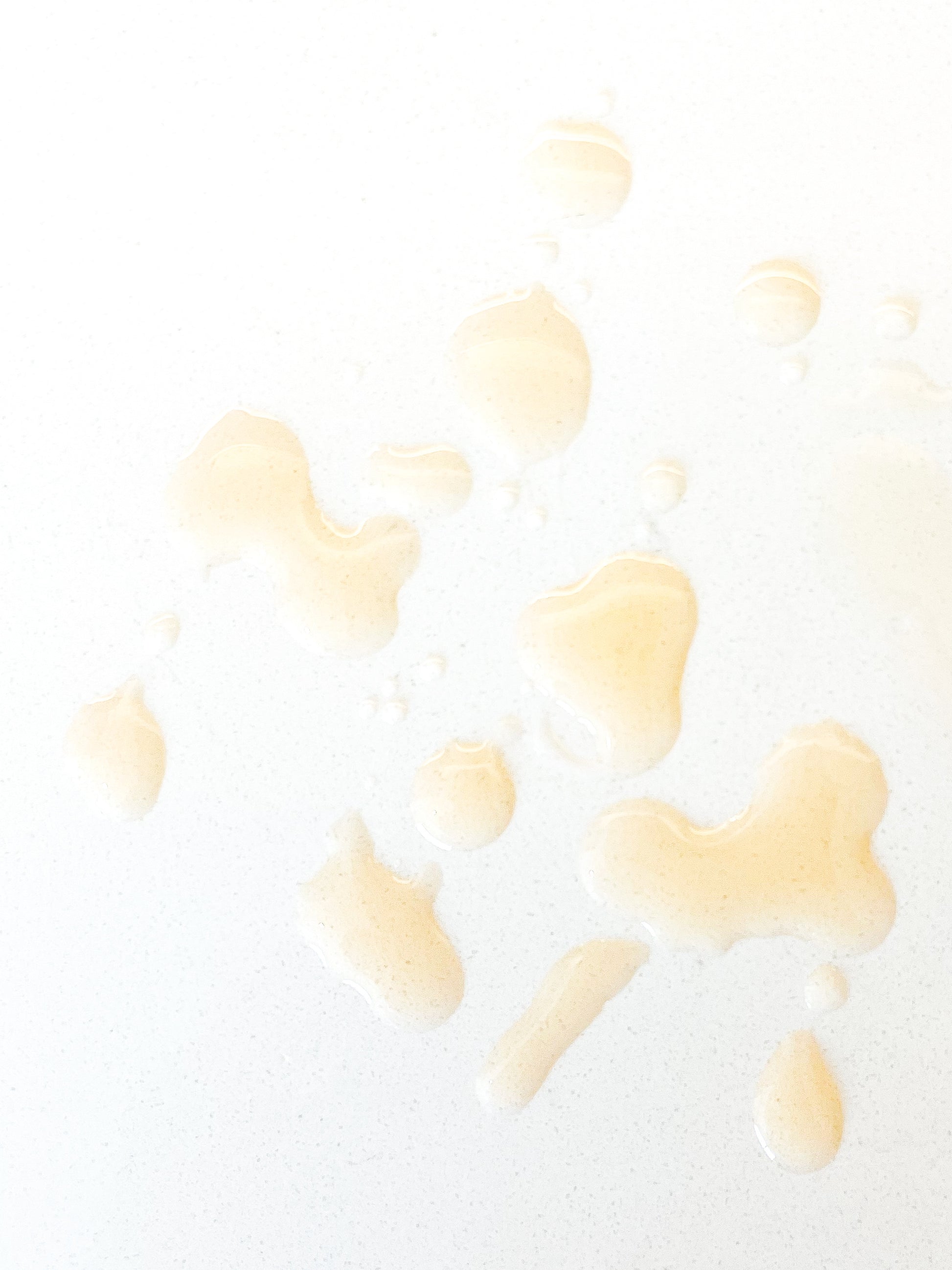 Close-up of gold oil drops on a white background