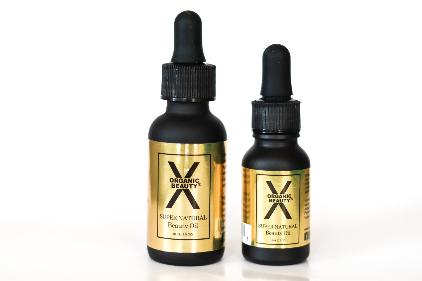 A 1 ounce and 1/2 ounce bottle of X Organic Beauty's Super Natural Beauty Oil on a white background.