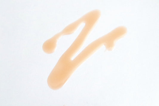 A z-shaped orange smear of X Organic Beauty's Super Natural Beauty Oil on a white background.