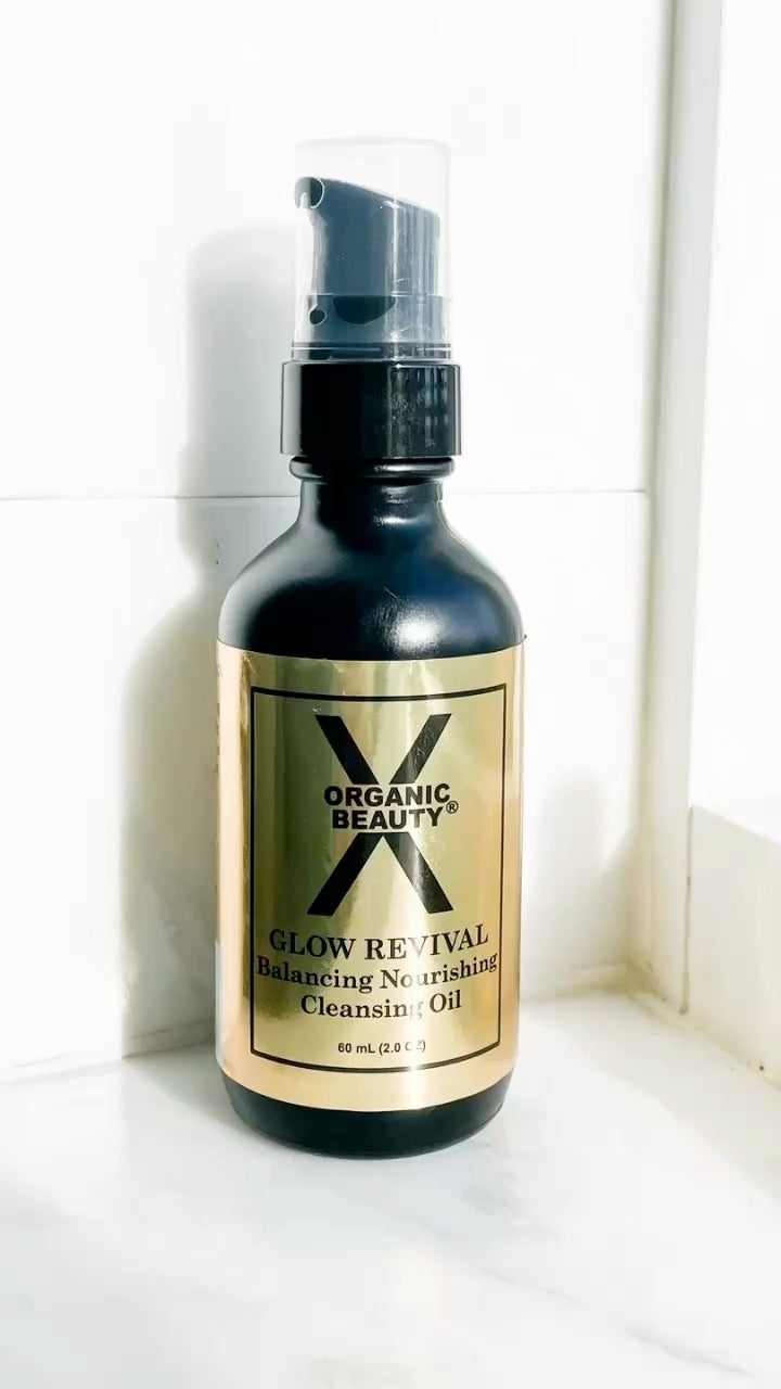 A video of a bottle of Organic Beauty Glow Revival Balancing Nourishing Cleansing Oill, standing on a white marble-like surface against a white tiled wall with the words: 3 Organic Ingredients: 1. Organic Jojoba Oil to lock in moisture. 2. Organic Evening Primrose Oil to support hormone balance. 3.  Organic Astaxanthin to feed your skin powerful antioxidant goodness.