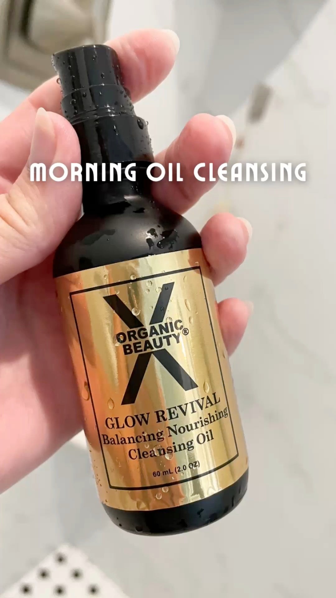 A video of a young lady demonstrating how to cleanse your face in the morning  with Organic Glow Revival Cleansing Oil, overlaid with the text 'MORNING OIL CLEANSING'.
